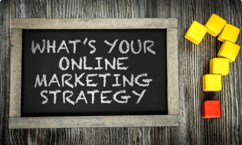 Notepad on a desk with the question ‘What’s your online marketing?’ written in marker, next to a laptop and coffee.
