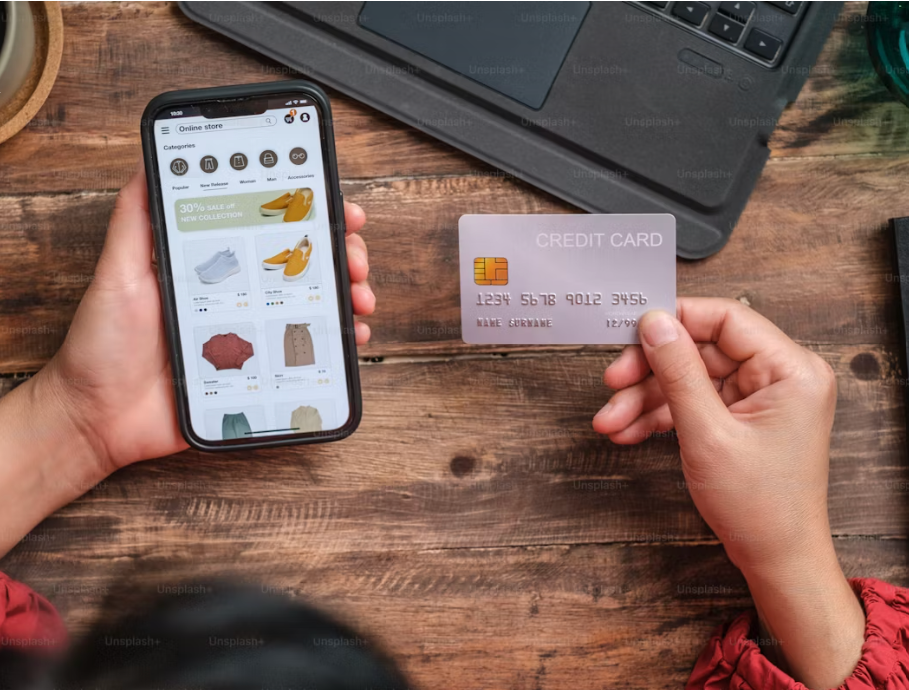 Close-up of a woman using a credit card to shop online with a mobile app at home, representing seamless e-commerce transactions.